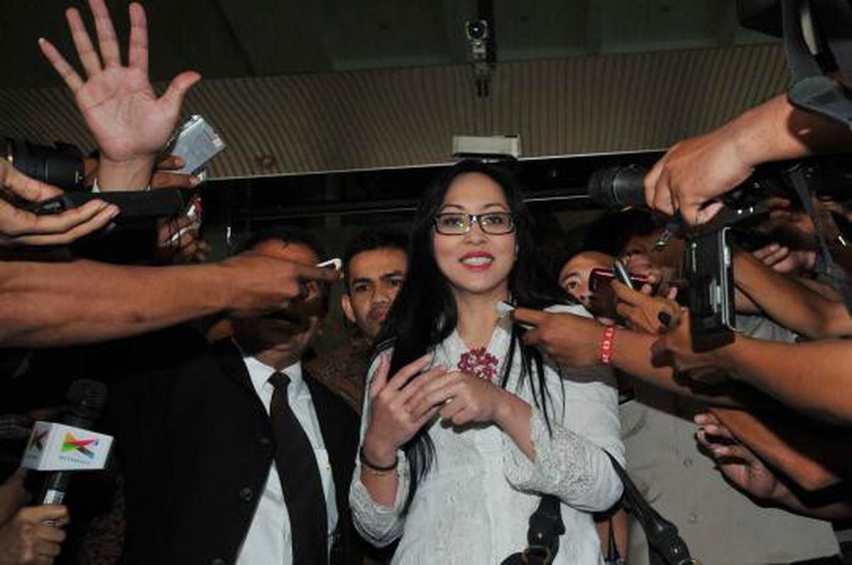 Angelina Sondakh tersenyum saat dikawal petugas keamanan KPK dan polis 