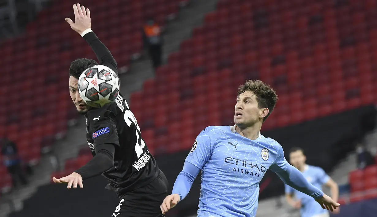 Bek Manchester City, John Stones berebut bola dengan bek Borussia Monchengladbach, Ramy Bensebani pada leg kedua babak 16 besar Liga Champions di Puskas Arena, Budapest, Rabu (17/3/2021) dini hari WIB. Menang 2-0, Manchester City merebut tiket perempat final. (Tibor Illyes/MTI via AP)