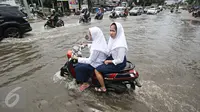 Dua orang pelajar berusaha menerobos banjir yang merendam Jalan Panjang, Jakarta Barat, Jumat (26/2). Hujan yang mengguyur wilayah Jakarta membuat sejumlah titik terendam banjir dengan ketinggian sekitar 20 cm - 1 meter. (Liputan6.com/ Immanuel Antonius)