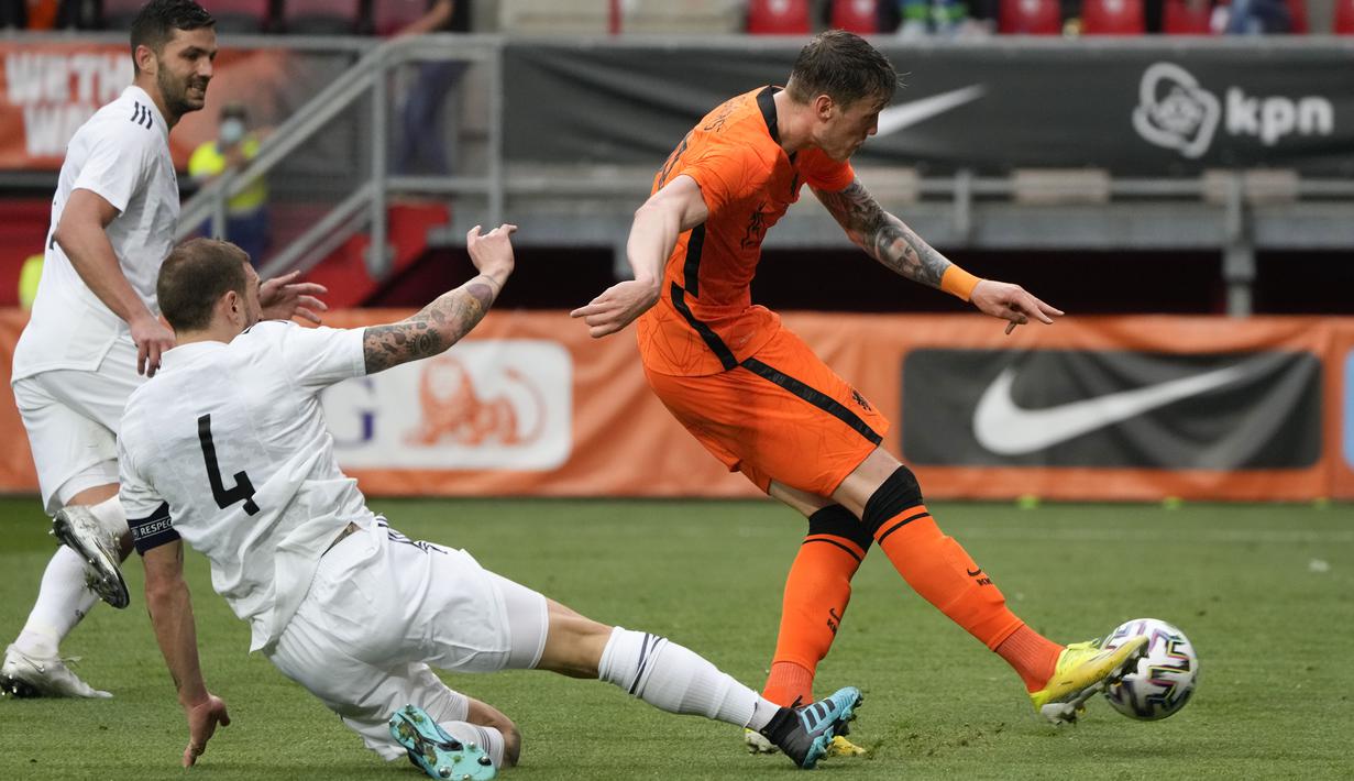 Penyerang timnas Belanda, Wout Weghorst mencetak gol kedua timnya saat pemain bek timnas Georgia, Guram Kashia berusaha memblokir tendangannya dalam pertandingan uji coba jelang Piala Eropa 2020 di De Grolsch Veste, Minggu (6/6/2021). Belanda menang meyakinkan 3-0. (AP Photo/Peter Dejong)