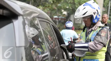 Petugas menilang pengendara mobil yang melanggar aturan pembatasan kendaraan sistem ganjil genap di kawasan Sudirman, Jakarta, Selasa (30/8). Hari ini resmi diberlakukan denda bagi pelanggar aturan sistem ganjil genap. (Liputan6.com/Yoppy Renato)