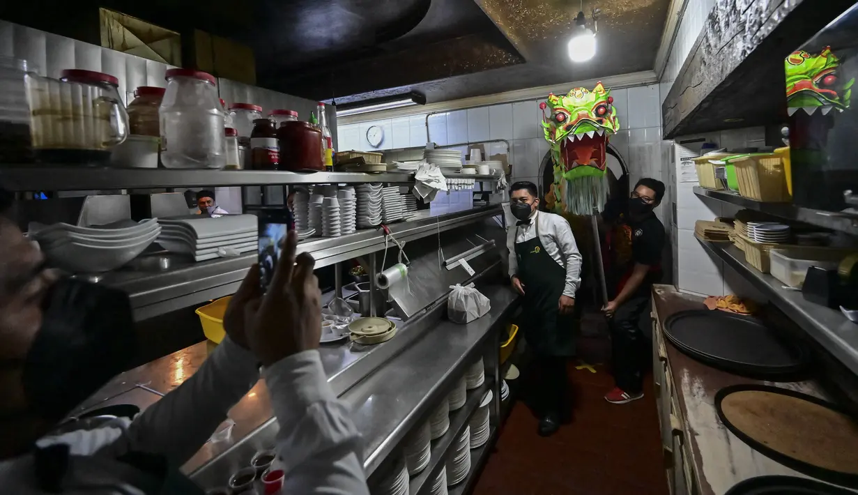 Anggota komunitas Tionghoa di Meksiko menampilkan tarian naga tradisional (liong) di sebuah restoran Tiongkok menyambut Tahun Baru Imlek di Mexico City, pada 31 Januari 2022. Tahun Baru Imlek 2022 menandai dimulainya tahun Shio Macan Air. (PEDRO PARDO / AFP)