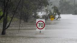 Rambu-rambu lalu lintas terendam di sepanjang jalan yang banjir di Londonderry di pinggiran Sydney, Australia, Senin (4/7/2022). Banjir kali ini merupakan yang terparah bagi kota terbesar di Australia tersebut selama 18 bulan terakhir. (AP Photo/Mark Baker)