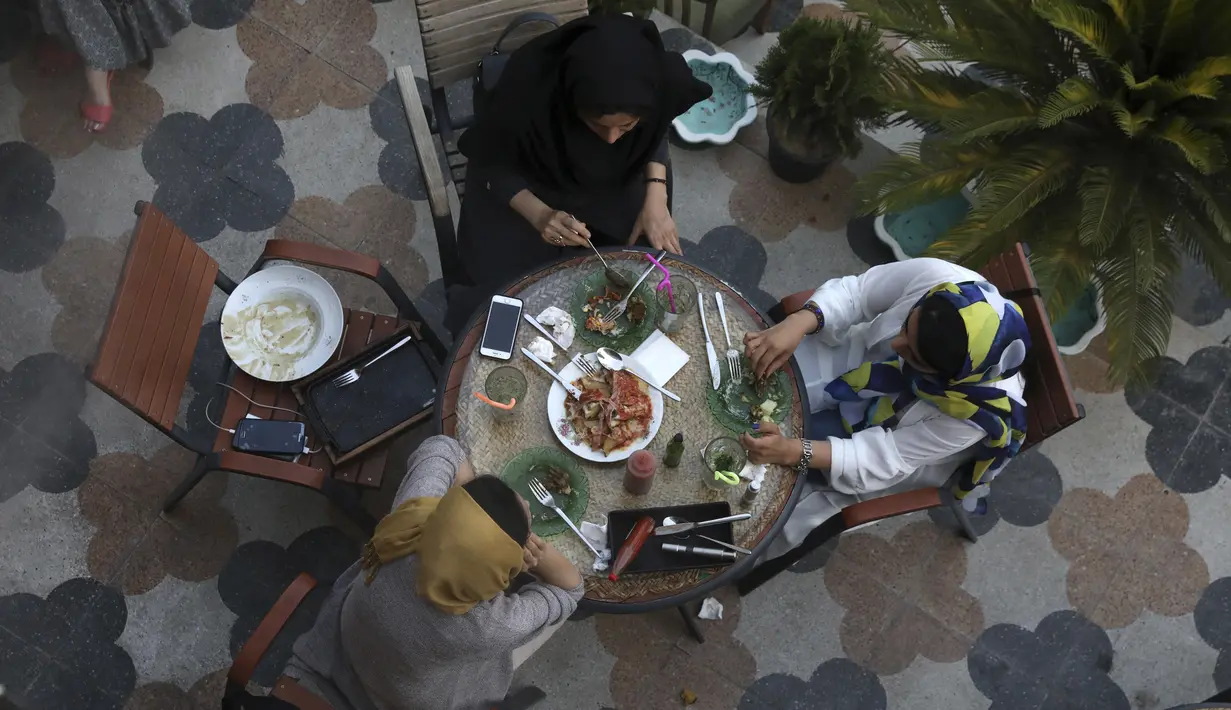 Tiga wanita menikmati hidangan saat sore hari di sebuah kafe di pusat kota Teheran, Iran (10/8/2019). Revolusi Islam 1979 membawa perubahan yang mengguncang Iran, tak terkecuali bagi kaum perempuan. (AP Photo/Vahid Salemi)