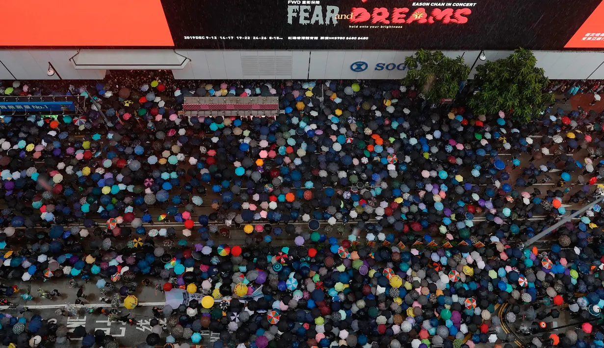 Pengunjuk rasa membawa payung saat menuju Victoria Park, Hong Kong, Minggu (18/8/2019). Puluhan ribu massa pro-demokrasi membawa payung saat hujan mengguyur Victoria Park dan sekitarnya. (AP Photo/Vincent Yu)