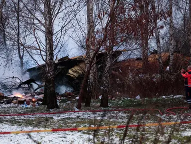 Seorang petugas medis mengambil foto dengan ponselnya dari puing-puing pesawat kargo yang jatuh di dekat Bandara Internasional Vilnius, Lithuania pada 25 November 2024. (Petras Malukas/AFP)