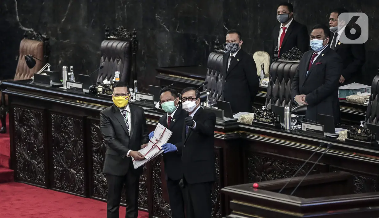 Ketua Komisi II Ahmad Doli Kurnia (kiri) memberikan salinan Perppu kepada Menkumham Yasonna Laoly dan Mendagri Tito Karnavian usai Rapat Paripurna ke-18 Masa Persidangan IV 2019-2020 di Kompleks Parlemen, Jakarta, Selasa (14/7/2020). Perppu Pilkada disahkan menjadi UU. (Liputan6.com/Johan Tallo)