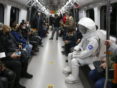 Seorang pria berpakaian astronaut naik metro sebagai bagian dari kampanye untuk mempromosikan Pameran Luar Angkasa NASA di Istanbul, Turki, pada 4 Desember 2021. Pameran ini akan menampilkan modul khusus dari luar angkasa dan puluhan instrumen berteknologi tinggi. (AP Photo/Emrah Gurel)