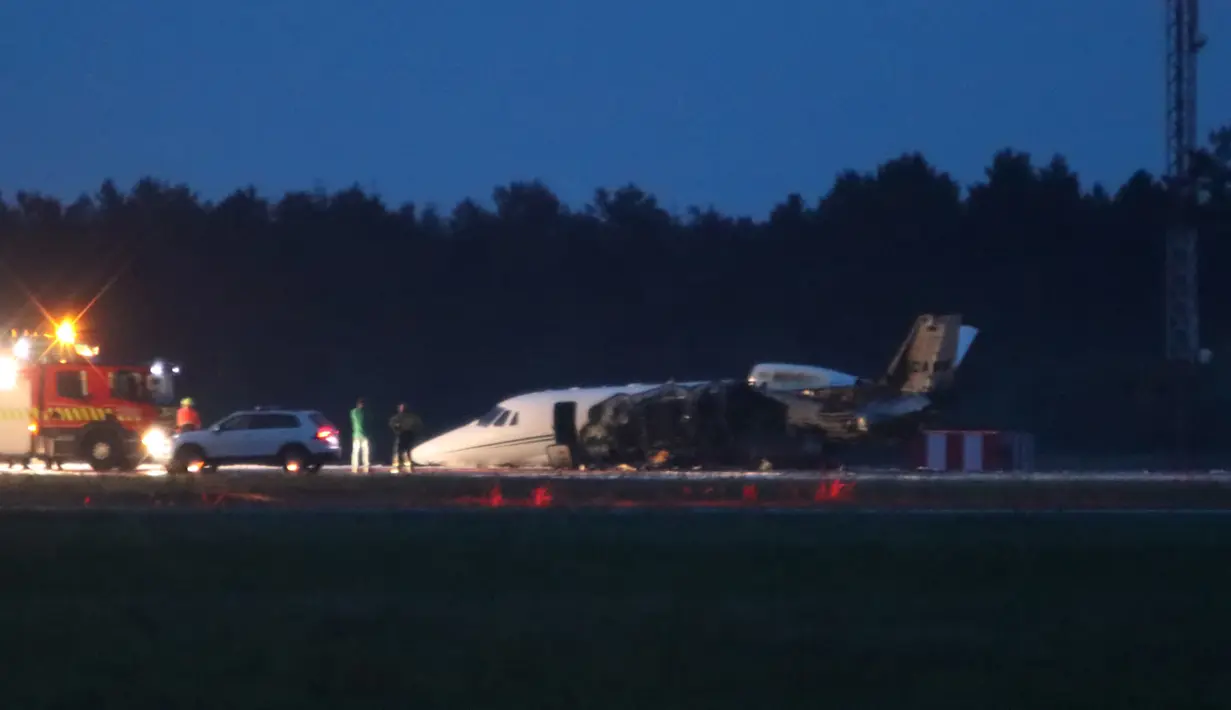Layanan darurat terlihat di sebelah pesawat Cessna 560XL yang terbakar saat mendarat di Bandara Aarhus di Tirstrup (6/8/2019). Tidak ada korban jiwa akibat kecelakaan pesawat yang terbakar pada pukul 00.38 di malam hari. (Oexenholt Foto/Ritzau Scanpix/AFP)