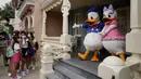 Pengunjung yang mengenakan masker berbaris untuk berswafoto dengan karakter kartun Donald Duck dan Daisy Duck di Disneyland Hong Kong pada Jumat (25/9/2020). Setelah dibuka dan tutup kembali, Disneyland Hong Kong dibuka kembali untuk wisatawan. (AP Photo/Kin Cheung)