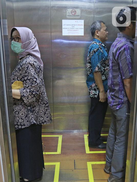 Sejumlah orang menaiki lift yang telah dipasangi garis batas dan saling membelakangi di PMI DKI Jakarta, Jumat (20/3/2020). PMI DKI Jakarta memberlakukan disiplin saling menjaga jarak atau social distancing sebagai langkah untuk mengantisipasi penyebaran COVID-19. (Liputan6.com/Herman Zakharia)