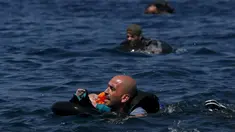 Seorang pengungsi Suriah membawa bayi menggunakan pelampung dan berenang menuju pantai setelah perahu yang ditumpangi bocor sekitar 100 m sebelum mencapai pulau Lesbon, Yunani, Minggu (13/09/2015). (REUTERS/Alkis Konstantinidis) 