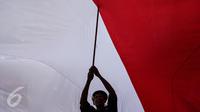Seorang peserta 'Aksi Kita Indonesia' ikut membentangkan Bendera Merah Putih raksasa di Bundaran HI, Jakarta, Minggu (4/12). Aksi Kita Indonesia adalah acara perayaan kegembiraan atas keberagaman dan kebangsaan Indonesia. (Liputan6.com/Fery Pradolo)