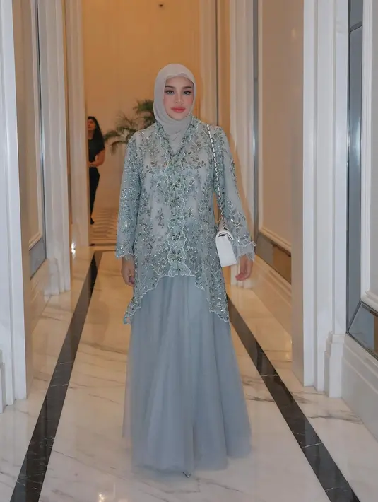 Penampilannya dilengkapi dengan hijab chiffon warna light grey dan sling bag berwarna putih. [@aurelie.hermansyah/@aaliyah.massaid].