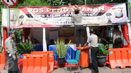 Petugas memasang spanduk di posko penjagaan Gereja Katedral, Jakarta, Sabtu (24/12). Penjagaan dilakukan untuk menjaga kondusifitas agar acara Malam Misa Natal bisa berjalan lancar. (Liputan6.com/Helmi Afandi) 