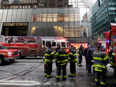Kendaraan dan para petugas pemadam berada di lokasi kebakaran di Fifth Avenue, depan Trump Tower, di New York, Senin (8/1). Kebakaran yang mengakibatkan dua orang luka-luka tersebut berasal dari pendingin di bagian atas gedung. (AP Photo/Richard Drew)