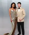Pasangan power couple, Priyanka Chopra dan Nick Jonas, kembali membuktikan status mereka sebagai fashion icon. Priyanka mengenakan gaun metalik rancangan Stella McCartney dengan aksen fur yang dramatis, sementara Nick tampil sleek dalam tuxedo krem yang clean. Keduanya menghadirkan harmoni antara bold femininity dan refined masculinity.
