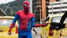 Jahn Fredy Duque menerima uang usai aksi di jalanan Bogota, Kolombia, Senin (24/4). Duque mencari nafkah dengan melakukan atraksi layaknya Spiderman. (AFP Photo/RAUL ARBOLEDA)