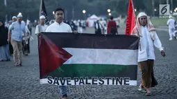 Peserta Aksi membawa bendera Palestina di kawasan silang Monas, Jakarta, Minggu (17/12). Massa dari berbagai daerah ini datang atas ajakan Majelis Ulama Indonesia (MUI). (Liputan6.com/Faizal Fanani)