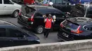 Pedagang asongan menjajakan barang dagangannya di persimpangan lampu merah di Jakarta, Jumat (22/2). Keahlian yang terbatas menyebabkan sebagian orang harus bekerja di tengah padatnya kendaraan Ibukota. (Liputan6.com/Immanuel Antonius)
