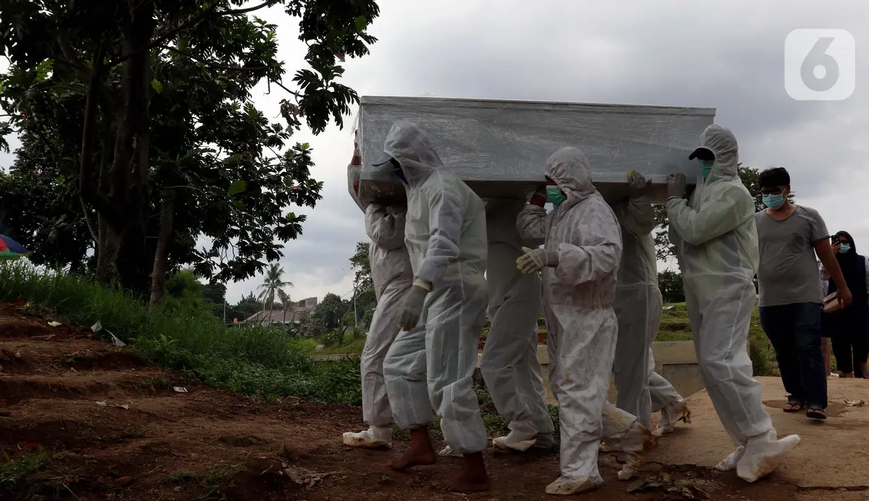 Petugas membawa peti jenazah yang akan dimakamkan dengan protokol COVID-19 di area khusus TPU Srengseng Sawah, Jakarta, Kamis (14/1/2021). TPU ini digunakan untuk memakamkan jenazah dengan protokol COVID-19 karena TPU Tegal Alur dan Pondok Ranggon sudah penuh. (Liputan6.com/Helmi Fithriansyah)
