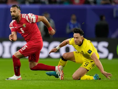 Pemain Yordania Yazan Alarab (kiri) mengincar bola saat pemain Malaysia Darren Lok terjatuh pada pertandingan sepak bola Grup E Piala Asia di Stadion Al Janoub, Al Wakrah, Qatar, Senin (15/1/2024). (AP Photo/Aijaz Rahi)