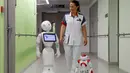Seorang perawat berjalan bersama robot humanoid bernama Pepper (kiri) dan Zora di rumah sakit AZ Damiaan ,Ostend , Belgia, (16/6). Robot ini dirancang atau dibuat untuk mengurus pasien yang datang ke rumah sakit. (REUTERS / Francois Lenoir)