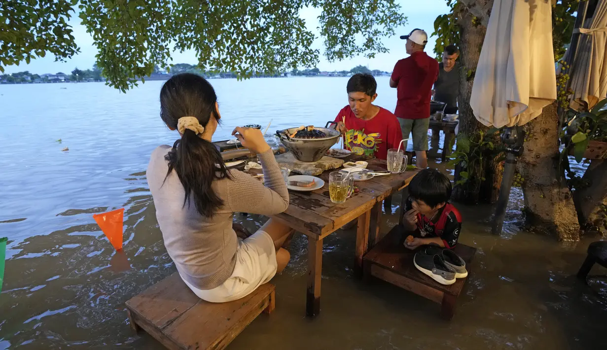 Pelanggan menyantap makanan di tengah banjir yang merendam Chaopraya Antique Café di Sungai Chao Phraya, Bangkok, Thailand, Kamis (7/10/2021). Alih-alih kursi kosong dan meja kosong justru restoran penuh seperti biasanya bagi para pencinta santapan 'hot-pot'. (AP Photo/Sakchai Lalit)