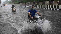 Pengendara motor melewati jalan yang tergenang air saat hujan lebat di New Delhi, India (1/9/2021). Stasiun cuaca mencatat curah hujan 112,1 mm dalam 24 jam yang berakhir pada hari Rabu pukul 08.30 waktu setempat. (AFP/Prakash Singh)