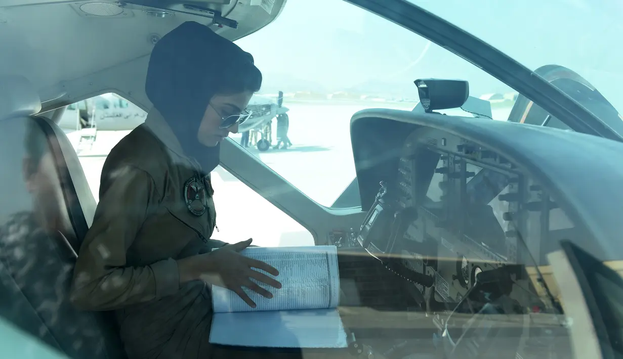 Niloofar Rahmani mengecek buku pesawat saat berada ruang kokpit jet Angkatan Udara Afghanistan di Kabul. Niloofar Rahmani diketahui baru saja menyelesaikan kursusnya selama 18 bulan di Negeri Paman Sam. (AFP PHOTO/SHAH Marai)