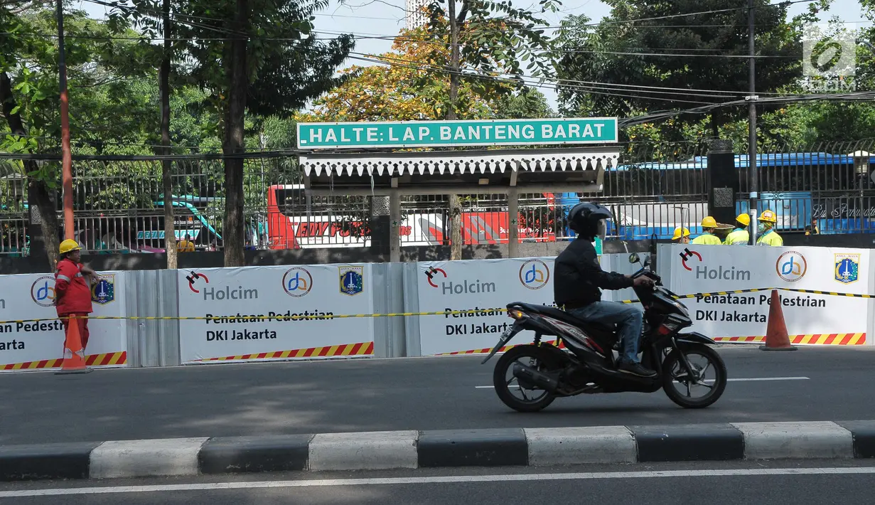Seorang pengendara motor melintas di sebelah proyek pembangunan pedestrian di Jalan Lapangan Banteng, Jakarta, Minggu (16/7). (Liputan6.com/Helmi Afandi)