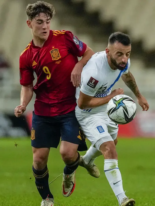 Gelandang timnas Spanyol Gavi berebut bola dengan gelandang Yunani Manolis Siopis pada laga Kualifikasi Piala Dunia 2022 zona Eropa Grup B di Olympic stadium, Jumat (12/11/2021) dini hari WIB. Spanyol menaklukkan tuan rumah Yunani dengan skor 1-0. (AP Photo/Thanassis Stavrakis)