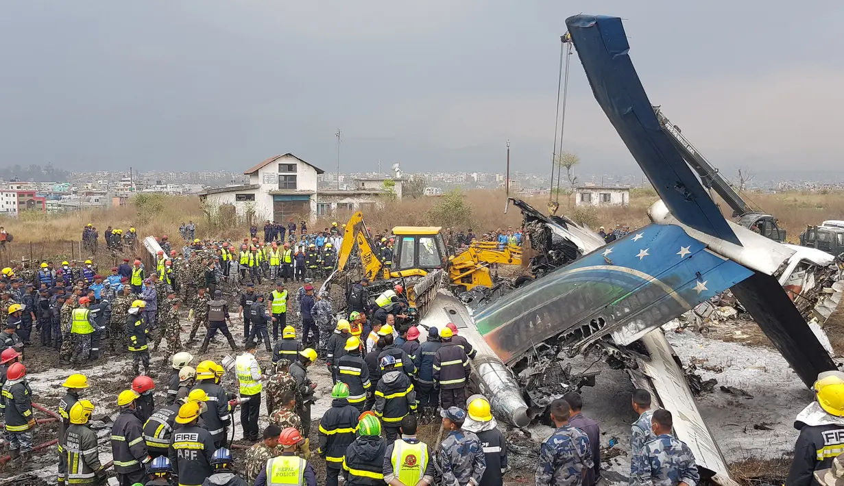 Tim penyelamat berkumpul di sekitar puing pesawat yang jatuh di dekat Bandara Internasional Kathmandu, Nepal, Senin (12/3). Sebanyak 40 orang tewas dan 23 lainnya cedera. (Prakash MATHEMA/AFP)