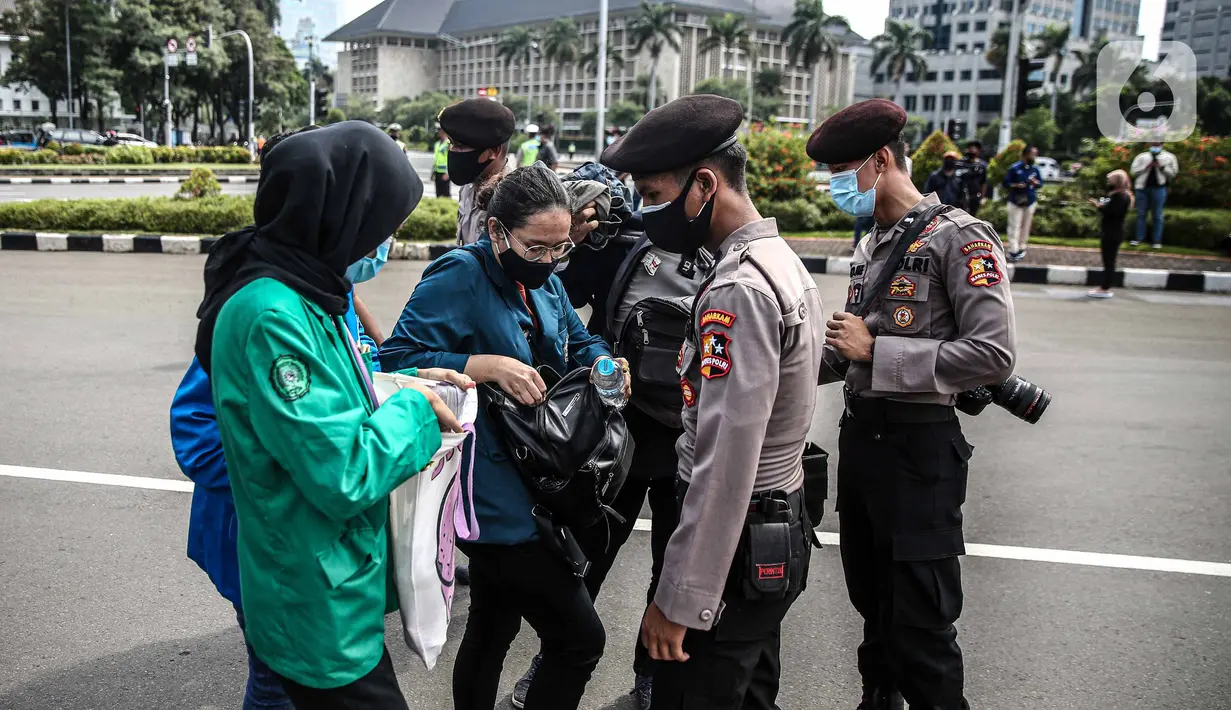 Polisi memeriksa barang bawaan mahasiswa yang akan berunjuk rasa di Patung Kuda, Jakarta, Selasa (20/10/2020). Pemeriksaan tersebut dilakukan untuk memastikan unjuk rasa berjalan aman dan damai. (Liputan6.com/Faizal Fanani)