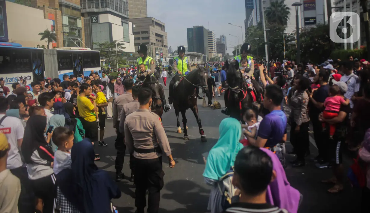 Antusiasme warga saat menyaksikan Polisi berkuda dari Direktorat Polisi Satwa Mabes Polri yang mengawasi keamanan di kawasan Bundaran HI, Jakarta, Minggu (17/11/2019). Polisi berkuda tersebut khusus ditugaskan mengawasi keamanan CFD serta memperkenalkan kepada warga. (Liputan6.com/Faizal Fanani)