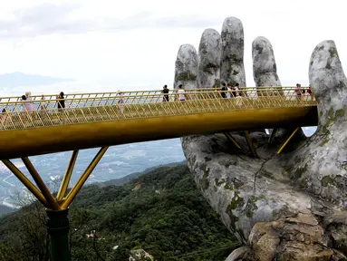 Pengunjung berjalan di sepanjang Golden Bridge di Perbukitan Ba Na dekat Danang, Vietnam, Selasa (31/7). Golden Bridge juga disebut-sebut sebagai Jembatan Tangan Tuhan karena ada dua tangan raksasa yang menopangnya. (Linh PHAM/AFP)