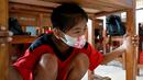 Seorang anak berlindung di bawah meja untuk melindungi dirinya selama latihan gempa dan tsunami di Tanjung Benoa, Kabupaten Badung, Bali, 24 Mei 2022. (SONY TUMBELAKA/AFP)