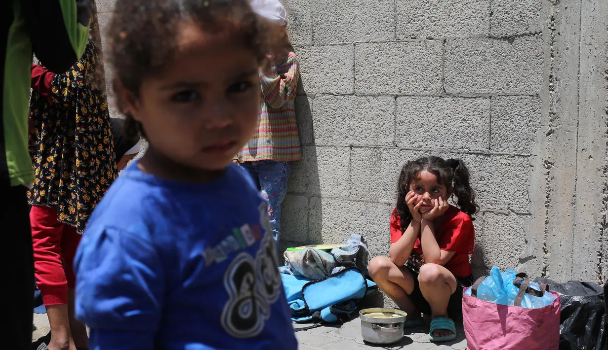 Anak-anak Palestina menunggu di dekat dapur umum yang membagikan makanan siap saji di kamp pengungsi Nuseirat di Jalur Gaza tengah pada 5 Mei 2025. (Eyad BABA/AFP)