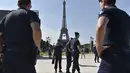 Sejumlah polisi melakukan penjagaan jelang acara Champs de Mars yang digelar untuk menyambut Piala Eropa 2016 di Paris fan zone, belakang Menara Eiffel, Prancis, Jumat (10/6/2016). (AFP/Alain Jocard)