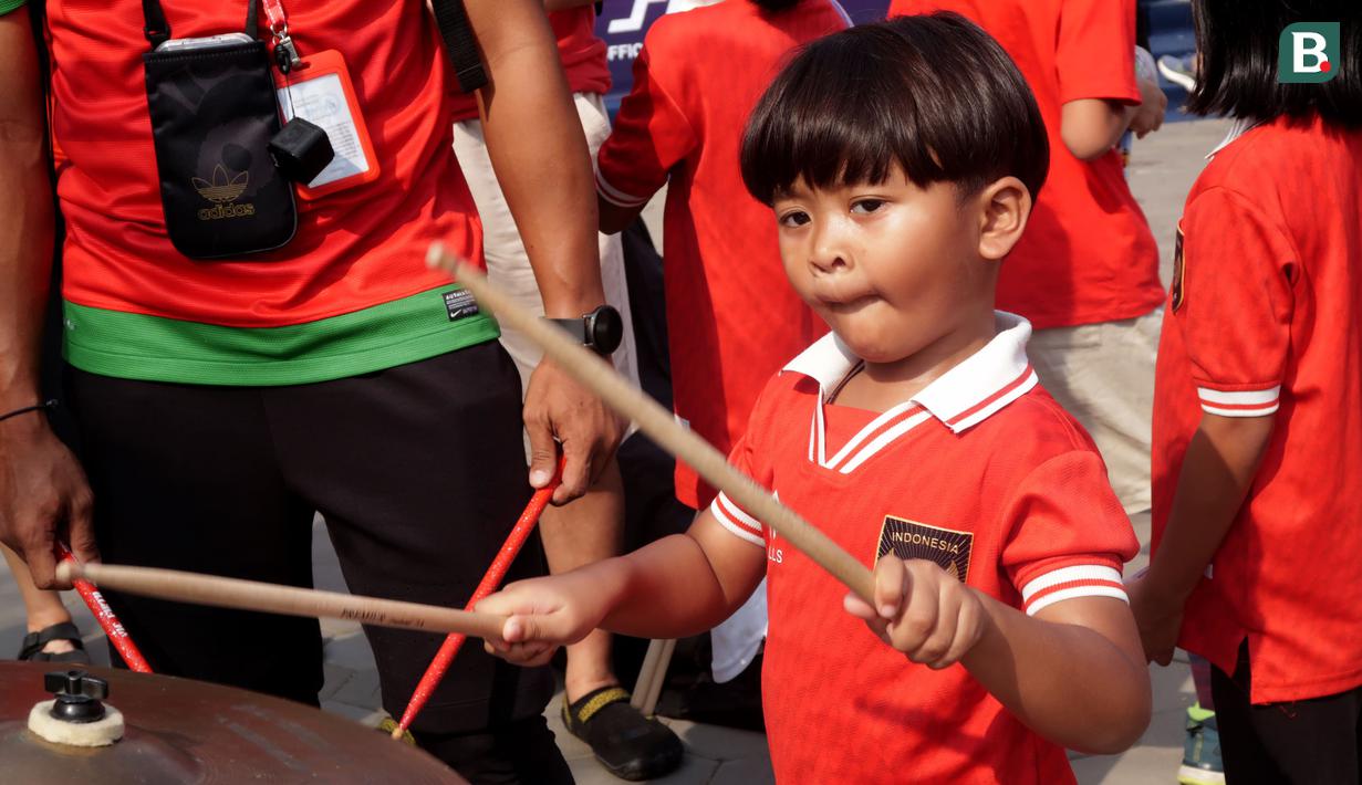 Seorang pendukung cilik Indonesia memukul simbal drum saat menunggu laga kedua Grup A Sepak Bola SEA Games 2023 antara Timnas Indonesia melawan Timnas Myanmar di Olympic Stadium, Phnom Penh, Kamboja, Kamis (04/05/2023). Skuad asuhan Indra Sjafri tersebut berhasil menang dengan skor telak 5-0. (Bola.com/Gregah Nurikhsani)