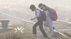 Anak-anak sekolah mengenakan masker berjalan melintasi rel kereta api di tengah kabut asap tebal di Lahore, Pakistan pada Rabu 20 November 2024. (Arif ALI/AFP)