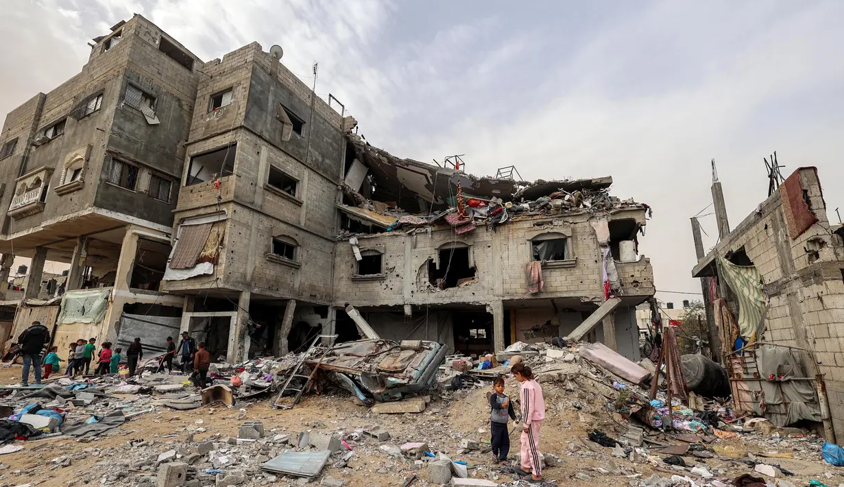 Anak-anak berdiri di luar gedung keluarga Sabah yang terkena serangan udara Israel di Deir el-Balah, Jalur Gaza tengah pada 8 April 2025. (Eyad BABA/AFP)