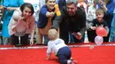 Orang tua mengiming-imingi bayi saat mengikuti lomba merangkak untuk memperingati Hari Anak Internasional di Vilnius, Lithuania, Kamis (1/6). Orang tua memberikan iming-iming benda kesukaan buah hatinya saat mengikuti lomba. (Petras Malukas/AFP)