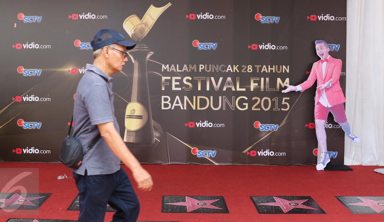 Seorang pria berjalan melintasi banner Festival Film Bandung (FFB) 2015 yang terpasang di Monumen Perjuangan Rakyat, Bandung, Sabtu (12/9/2015). (Liputan6.com/Herman Zakharia)