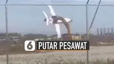 Alat berat itu menjepit rongsokan badan pesawat dan memutar-mutarnya seperti wahana taman rekreasi.