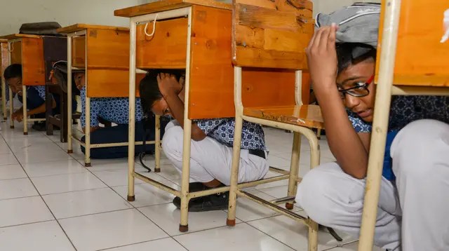 Sejumlah siswa berlindung di bawah meja saat simulasi bencana gempa dan tsunami di sebuah sekolah di Banda Aceh, Aceh, Rabu (9/10/2019). Simulasi dilakukan karena Aceh merupakan daerah rawan kedua bencana tersebut dan turut merusak bangunan sekolah. (Photo by CHAIDEER MAHYUDDIN / AFP)