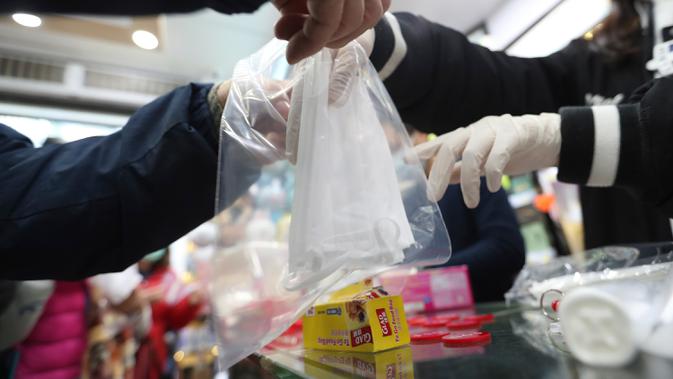 Warga menerima masker wajah gratis dalam sebuah toko di Tsuen Wan, Hong Kong, Selasa (28/1/2020). Hong Kong terkonfirmasi memiliki delapan kasus infeksi virus corona. (AP Photo/Achmad Ibrahim)