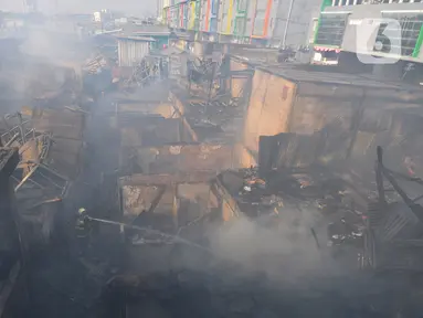 Petugas pemadam kebakaran melakukan pendinginan kawasan pemukiman padat penduduk yang terbakar di kawasan Manggarai, Jakarta, Selasa (13/8/2024). (merdeka.com/Imam Buhori)