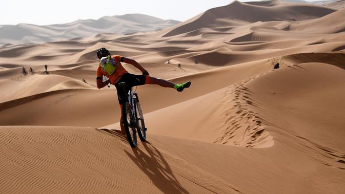 Pebalap mengendarai sepeda melintasi sepanjang bukit pasir pada etape 1 edisi ke 14 balap sepeda gunung Titan Gurun 2019 di sekitar Kota Merzouga, Maroko, Minggu (28/4/2019). Trek Titan Gurun 2019 sepanjang 640 km menghubungkan antara Merzouga dan Maadid. (Franck Fife / AFP)