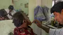 Dalam gambar yang diambil pada 19 Januari 2019, tukang cukur Mohammad Shadat Hossain mewarnai janggut pelanggannya dengan pacar (henna) di Dhaka. Penampilan ini didorong juga dengan kepercayaan terhadap tulisan-tulisan agama yang mengatakan Nabi Muhammad mengecat rambutnya. (MUNIR UZ ZAMAN / AFP)